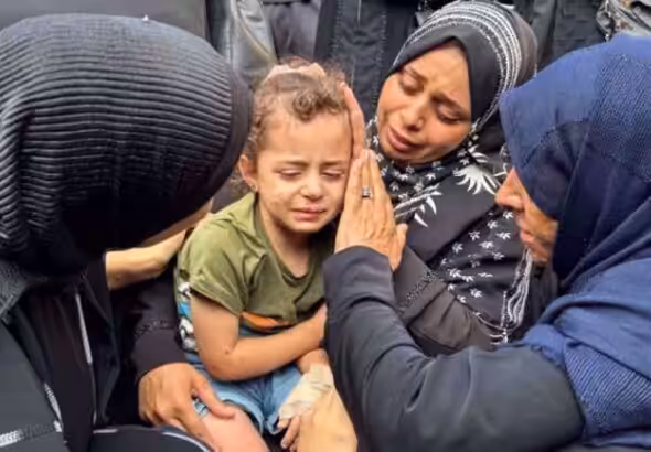 Mourners comfort a young girl at the funeral of Palestinians killed in Israeli strikes in Deir el-Balah, central Gaza, on June 28. Photo: Reuters.