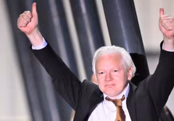 Julian Assange with his fists up on his arrival in Australia after almost 11 years of United States persecution for revealing the atrocities of the US military in Iraq and Afghanistan. Photo: AFP.