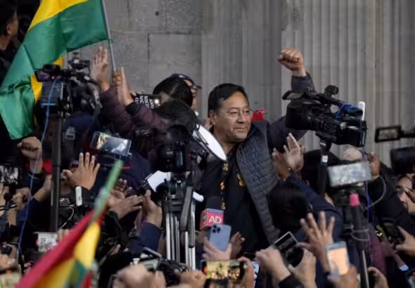 Bolivian President Luis Arce raises a clenched fist, surrounded by the public movements against the coup and by media, outside the government palace in La Paz, Bolivia, Wednesday, June 26, 2024. Photo: Juan Karita/AP.