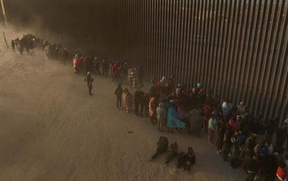 Migrants at border wall waiting to surrender to immigration officials in El Paso, TX, March 25, 2024. Photo: Reuters/Adrees Latif.