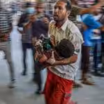 A paramedic carries a Palestinian child wounded during Israeli bombardment to the emergency ward at the Nassr Hospital in Khan Younis, southern Gaza Strip, July 9, 2024. Photo: AFP.