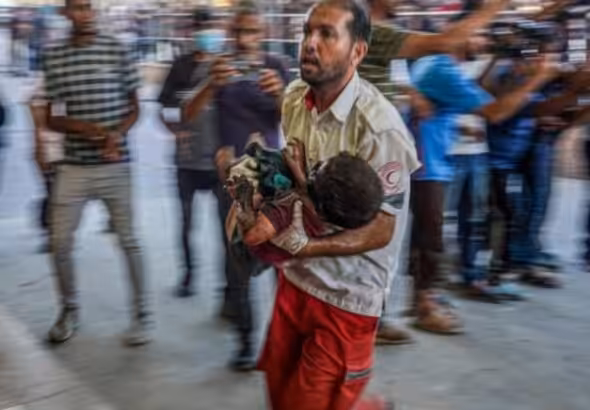 A paramedic carries a Palestinian child wounded during Israeli bombardment to the emergency ward at the Nassr Hospital in Khan Younis, southern Gaza Strip, July 9, 2024. Photo: AFP.