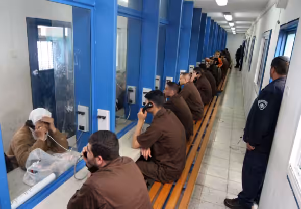 Palestinian prisoners talking to family or friends. Photo: Hagai Aharon/AFP/Getty Images.