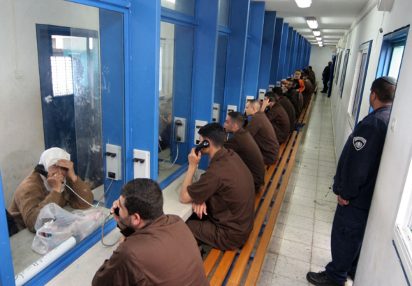 Palestinian prisoners talking to family or friends. Photo: Hagai Aharon/AFP/Getty Images.