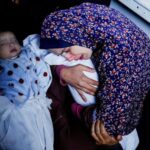 A Palestinian mother Rania Abu Anza holds one of her five-month old twins who were killed alongside her husband and 11 other relatives in an Israeli airstrike. Photo: @hamdahsalhut).