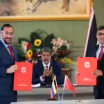 The minister for energy and energy industries of Trinidad and Tobago, Stuart Richard Young (left), and the minister for oil of Venezuela, Pedro Tellechea (right), displaying the signed energy cooperation agreements, with the president of Venezuela, Nicolás Maduro, applauding in the background at Miraflores Palace, Caracas, on July 24, 2024. Photo: Telesur.