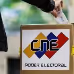 Person casting a paper ballot in a box with the logo of the Venezuelan National Electoral Council (CNE). Photo: File photo.