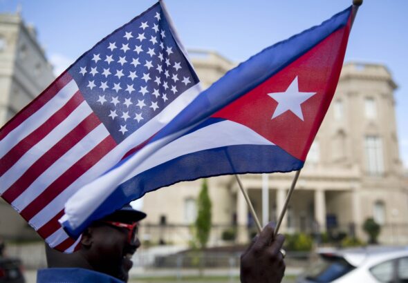 A person holding small US and Cuban flags in front of the Cuban embassy in Washington DC. Photo: Andrew Harrer/Bloomberg/file photo.