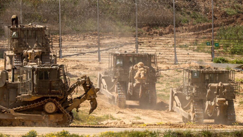 Fenced Israeli occupation bulldozers removing rubbish caused by incessant air strikes on Palestine and its people. Photo: Jack Guez/AFP.
