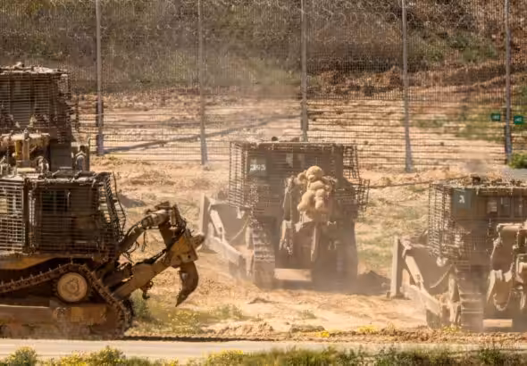 Fenced Israeli occupation bulldozers removing rubbish caused by incessant air strikes on Palestine and its people. Photo: Jack Guez/AFP.