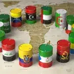 World map with barrels colored with the flags of oil producing countries. Photo: Maksym Yemelyanov/Adobe Stock.