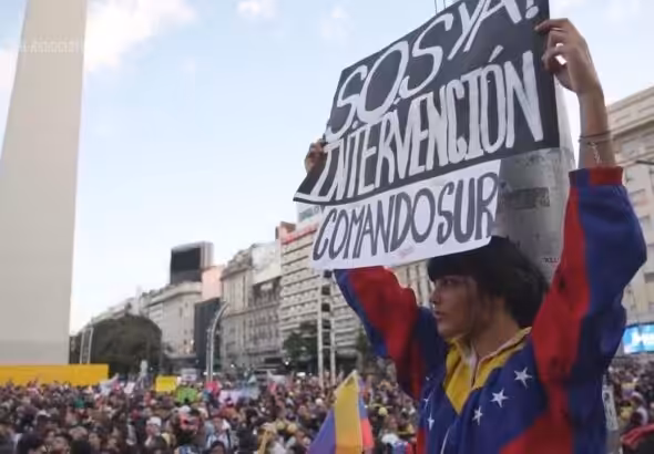 Opposition supporters demonstrating in Buenos Aires one of them holding a banner that reads “SOS, Intervention now, SouthCom.” Photo: AP.