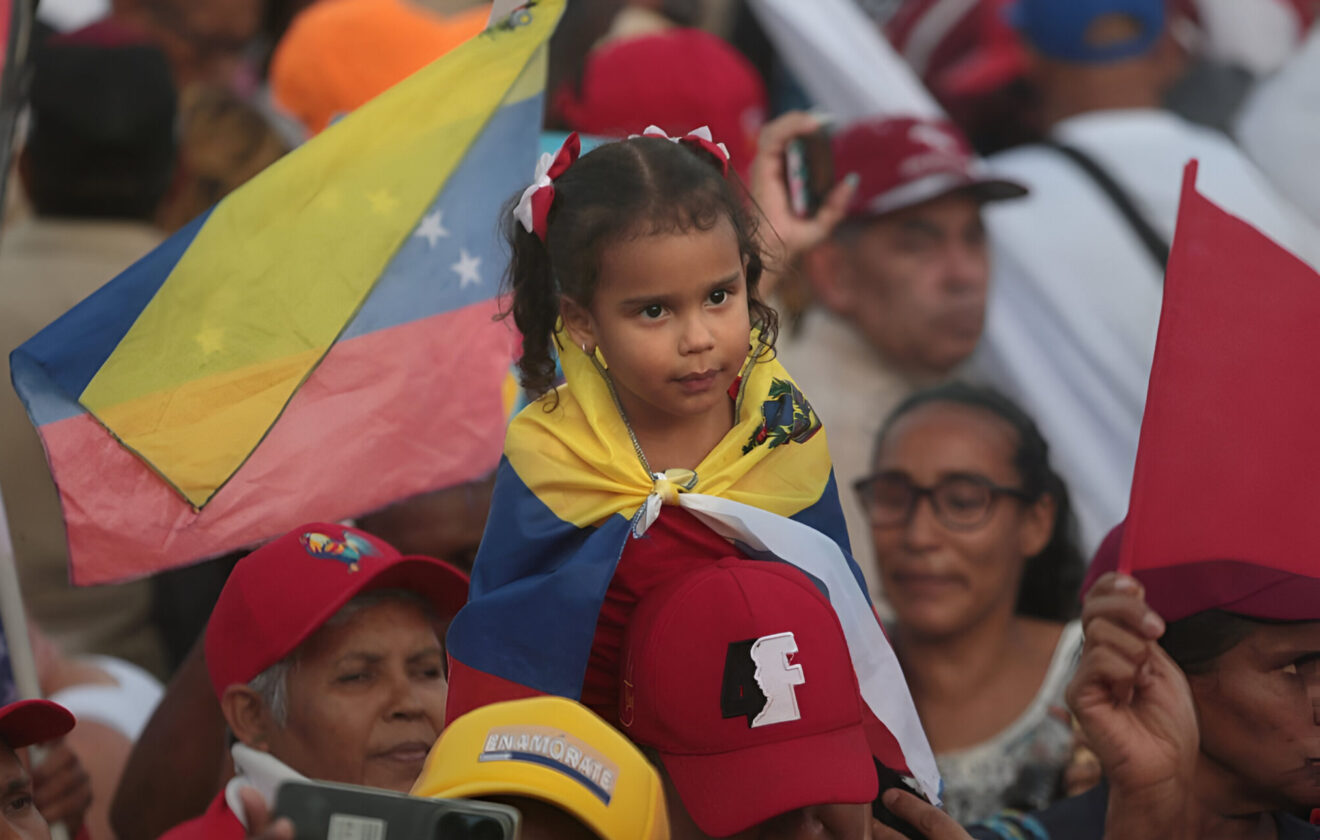 Girl covered with the Venezuelan flag seat on the shoulder of an adult during the massive closing rally of Preswident Nicolas Maduro at Bolivar Ave, Caraca, on Thursday, July 25, 2024. Photo: Yaimi Ravelo/Resumen Latinoamericano.