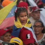 Girl covered with the Venezuelan flag seat on the shoulder of an adult during the massive closing rally of Preswident Nicolas Maduro at Bolivar Ave, Caraca, on Thursday, July 25, 2024. Photo: Yaimi Ravelo/Resumen Latinoamericano.