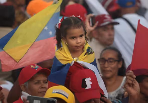 Girl covered with the Venezuelan flag seat on the shoulder of an adult during the massive closing rally of Preswident Nicolas Maduro at Bolivar Ave, Caraca, on Thursday, July 25, 2024. Photo: Yaimi Ravelo/Resumen Latinoamericano.