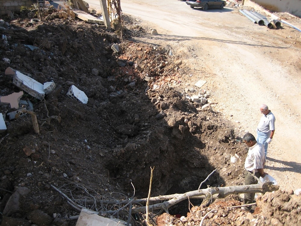 Dr. Ali Khobeisi (right) taking Geiger counter readings at a bomb crater in Khiam, Lebanon, 2006.