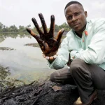 A Nigerian man holds up his hand to show oil sludge that has been polluting the Niger Delta region due to oil spills caused by the British petroleum giant Shell. Photo: The Guardian.
