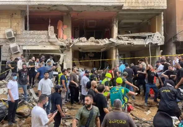 People gather near a damaged building at the scene of an Israeli missile strike in the Southern Suburb of Beirut on Friday, September 20, 2024. Photo: AP.