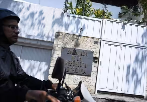 A biker passing by the entrance of the Argentinian embassy in Caracas. Photo: AFP.