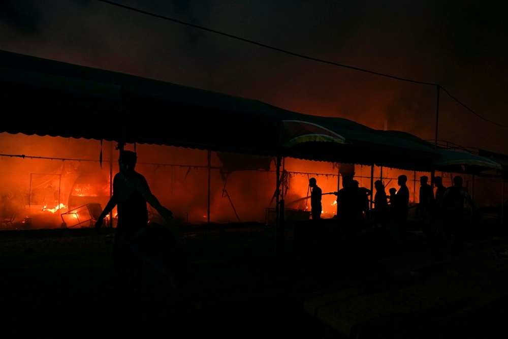 Palestinians try to extinguish a fire caused by Israeli airstrikes on tents in the courtyard of Al-Aqsa Martyrs Hospital, Deir al-Balah, central Gaza Strip, October 14, 2024. Photo: AP.
