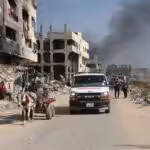 An ambulance drives through a devastated neighborhood in Gaza, passing by civilians using a horse-drawn cart amidst widespread destruction caused by ongoing airstrikes. Photo: AFP.