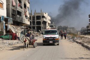 An ambulance drives through a devastated neighborhood in Gaza, passing by civilians using a horse-drawn cart amidst widespread destruction caused by ongoing airstrikes. Photo: AFP.