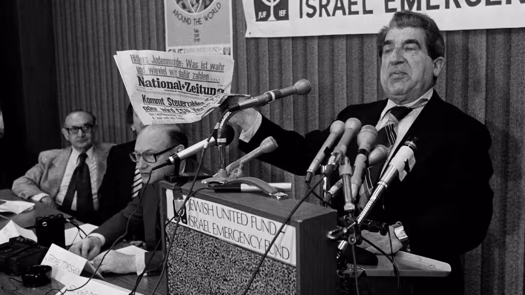 Sol Goldstein, spokesman for a group of Jewish organizations, holds up a German language newspaper with headlines questioning the validity of the Holocaust, at a news conference in Chicago, June 14, 1978. Photo: AP.