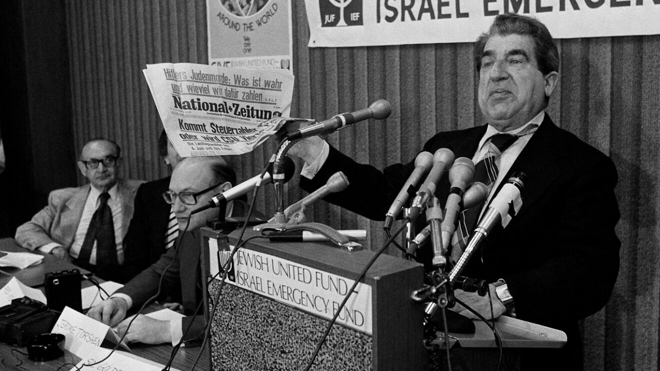Sol Goldstein, spokesman for a group of Jewish organizations, holds up a German language newspaper with headlines questioning the validity of the Holocaust, at a news conference in Chicago, June 14, 1978. Photo: AP.