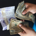 A person holds Venezuelan bolívars and US dollar bills. File photo.