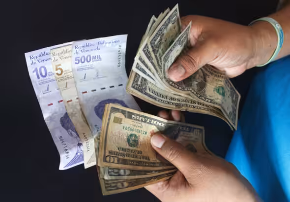 A person holds Venezuelan bolívars and US dollar bills. File photo.