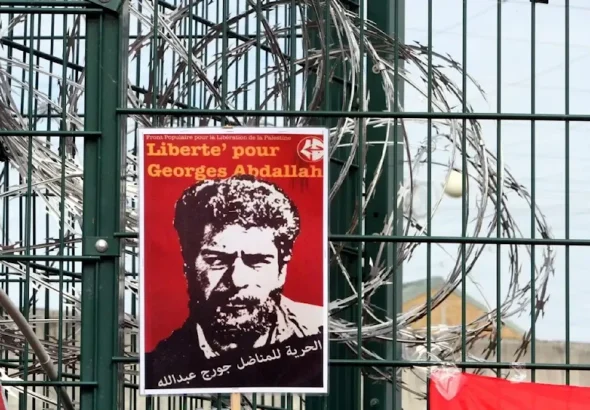 A poster reading 'Freedom for Georges Abdallah' is placed near razor wire on the gate outside the prison in southern France on October 25, 2014. Photo: AFP.