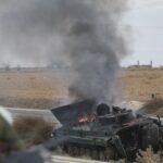 Extremist militants ride past an overturned Syrian army tank on fire. Photo: Ghaith Alsayed/AP.