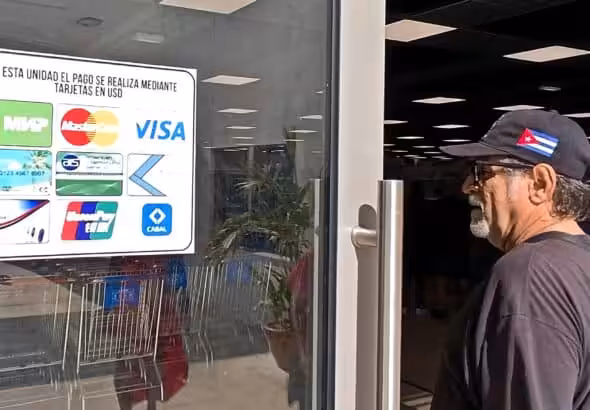 A man looks at a sign outside a shopping mall showing the types of cards accepted at the establishment, in Havana, Cuba. Photo: EFE.