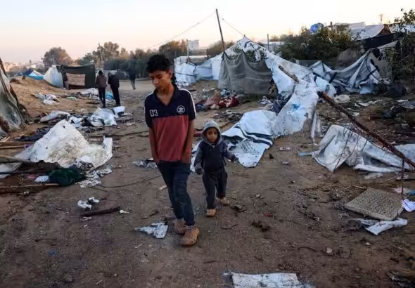 Palestinian children walk amid scattered debris in a tent camp in Khan Younis, southern Gaza Strip, after an overnight Israeli airstrike, January 2, 2025. Photo: AFP.