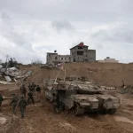 IOF soldiers walk by a tank during the ground invasion of the Gaza Strip in Khan Younis on Saturday, January 27, 2024. Photo: AP.