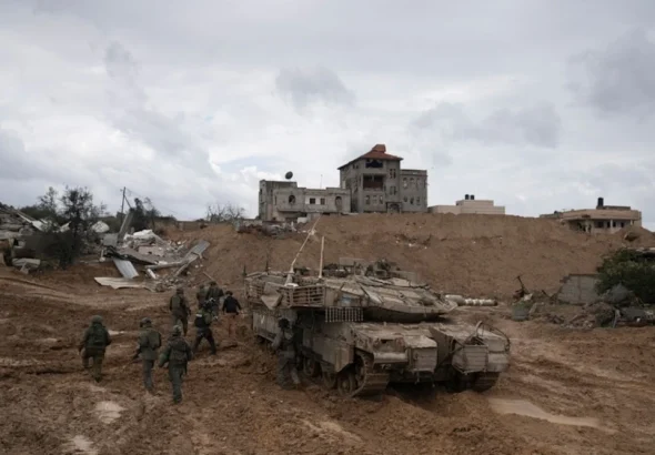 IOF soldiers walk by a tank during the ground invasion of the Gaza Strip in Khan Younis on Saturday, January 27, 2024. Photo: AP.