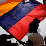 A woman holds a Venezuelan flag during a St. John the Baptist feast in the San Austin neighborhood of Caracas, Venezuela, Friday June 24, 2022. Photo: Matias Delacroix/AP Photo.