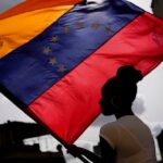 A woman holds a Venezuelan flag during a St. John the Baptist feast in the San Austin neighborhood of Caracas, Venezuela, Friday June 24, 2022. Photo: Matias Delacroix/AP Photo.