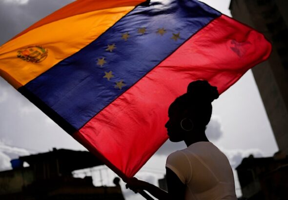 A woman holds a Venezuelan flag during a St. John the Baptist feast in the San Austin neighborhood of Caracas, Venezuela, Friday June 24, 2022. Photo: Matias Delacroix/AP Photo.