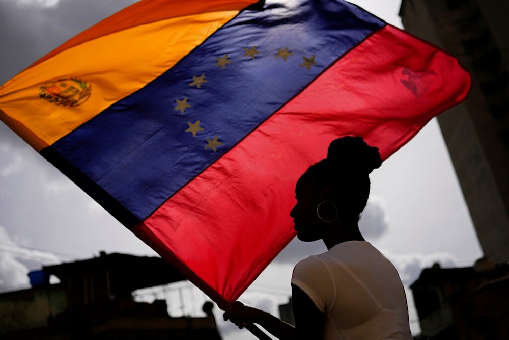 A woman holds a Venezuelan flag during a St. John the Baptist feast in the San Austin neighborhood of Caracas, Venezuela, Friday June 24, 2022. Photo: Matias Delacroix/AP Photo.
