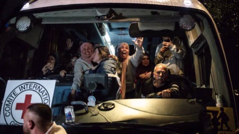 Palestinians freed from Israel’s Ofer military prison wave to the crowd from an International Committee of the Red Cross (ICRC) bus as they arrive in Beitunia, in the occupied West Bank on Monday morning. Photo: AFP.