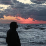 Palestinians walk on the beach during sunset on the last day of 2024 in Deir al-Balah in the central Gaza Strip, on 31 December 2024. Photo: Omar Ashtawy/APA images.