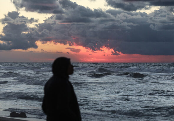 Palestinians walk on the beach during sunset on the last day of 2024 in Deir al-Balah in the central Gaza Strip, on 31 December 2024. Photo: Omar Ashtawy/APA images.