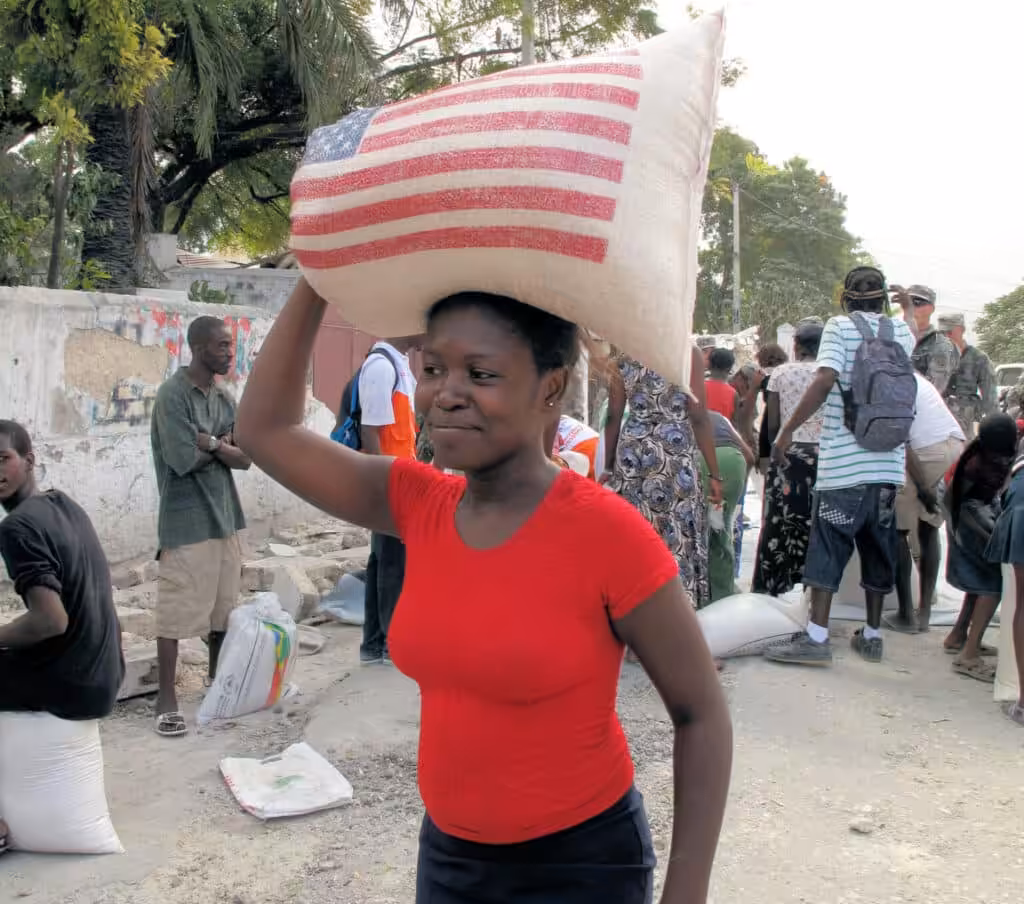 Woman carrying bag of USAID-provided rice on her head on Feb. 1, 2010, just weeks after the devastating earthquake. Photo: R. Gustafson/USAID.