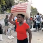 Woman carrying bag of USAID-provided rice on her head on Feb. 1, 2010, just weeks after the devastating earthquake. Photo: R. Gustafson/USAID.