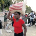 Woman carrying bag of USAID-provided rice on her head on Feb. 1, 2010, just weeks after the devastating earthquake. Photo: R. Gustafson/USAID.