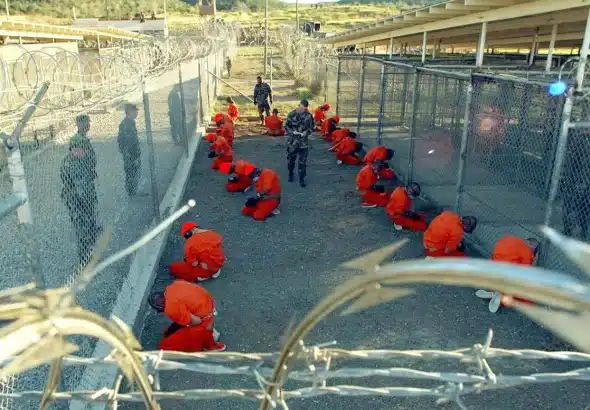 Detainees in the Guantánamo Bay Prison sit in a holding area at Camp X-Ray, January 11, 2002. Photo: Reuters/Shane T. McCoy.
