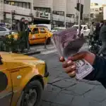 A person holds a handful of Syrian Pounds, in Damascus, Syria. Photo: AFP.