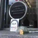 A placard reading "RIP USAID" and a bouquet of flowers placed before the USAID building in Washington, USA. Photo: AP/José Luis Magaña.