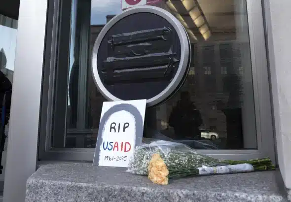 A placard reading "RIP USAID" and a bouquet of flowers placed before the USAID building in Washington, USA. Photo: AP/José Luis Magaña.